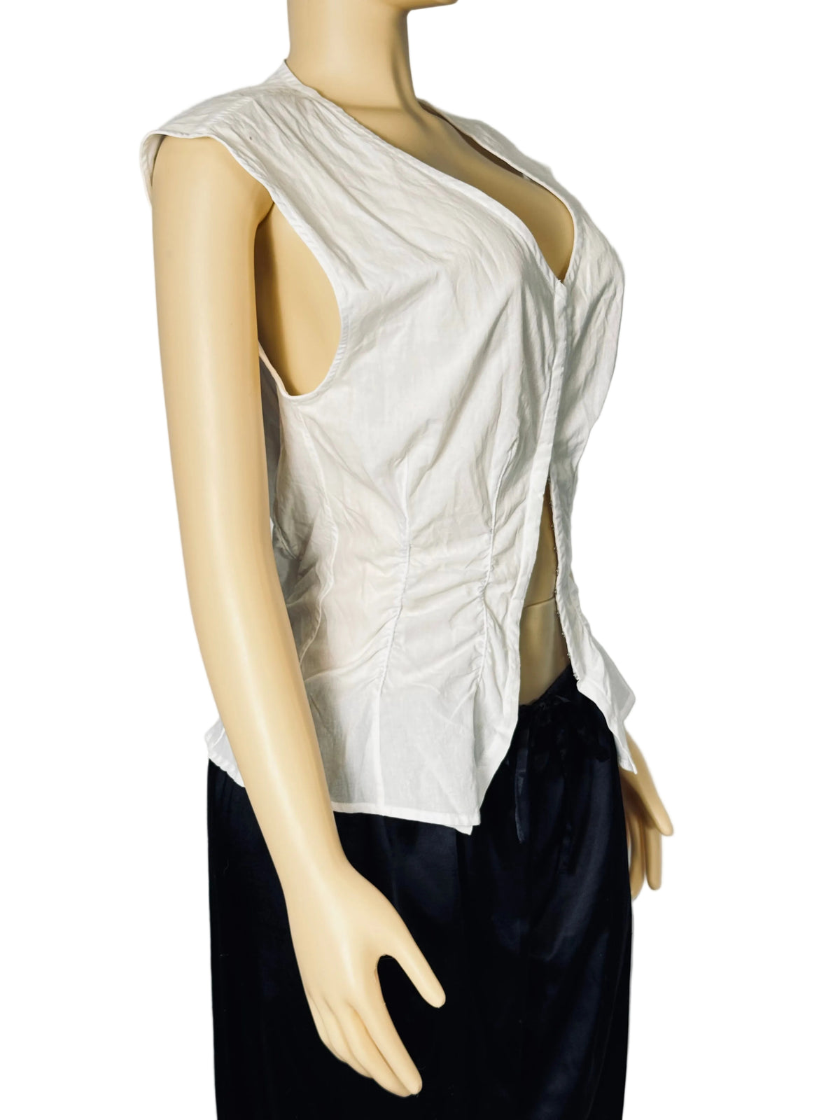 A sleeveless white wrap-style top with a deep V-neck and side slit, displayed on a beige mannequin torso against a light gray backdrop. The mannequin is also wearing dark navy bottoms.
