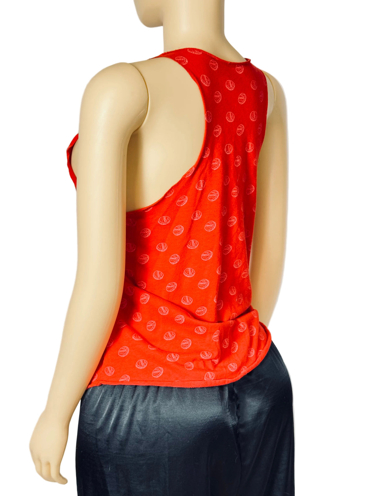 A red sleeveless tank top with a small white repeating pattern, shown from the back on a mannequin wearing dark pants against a white studio background.