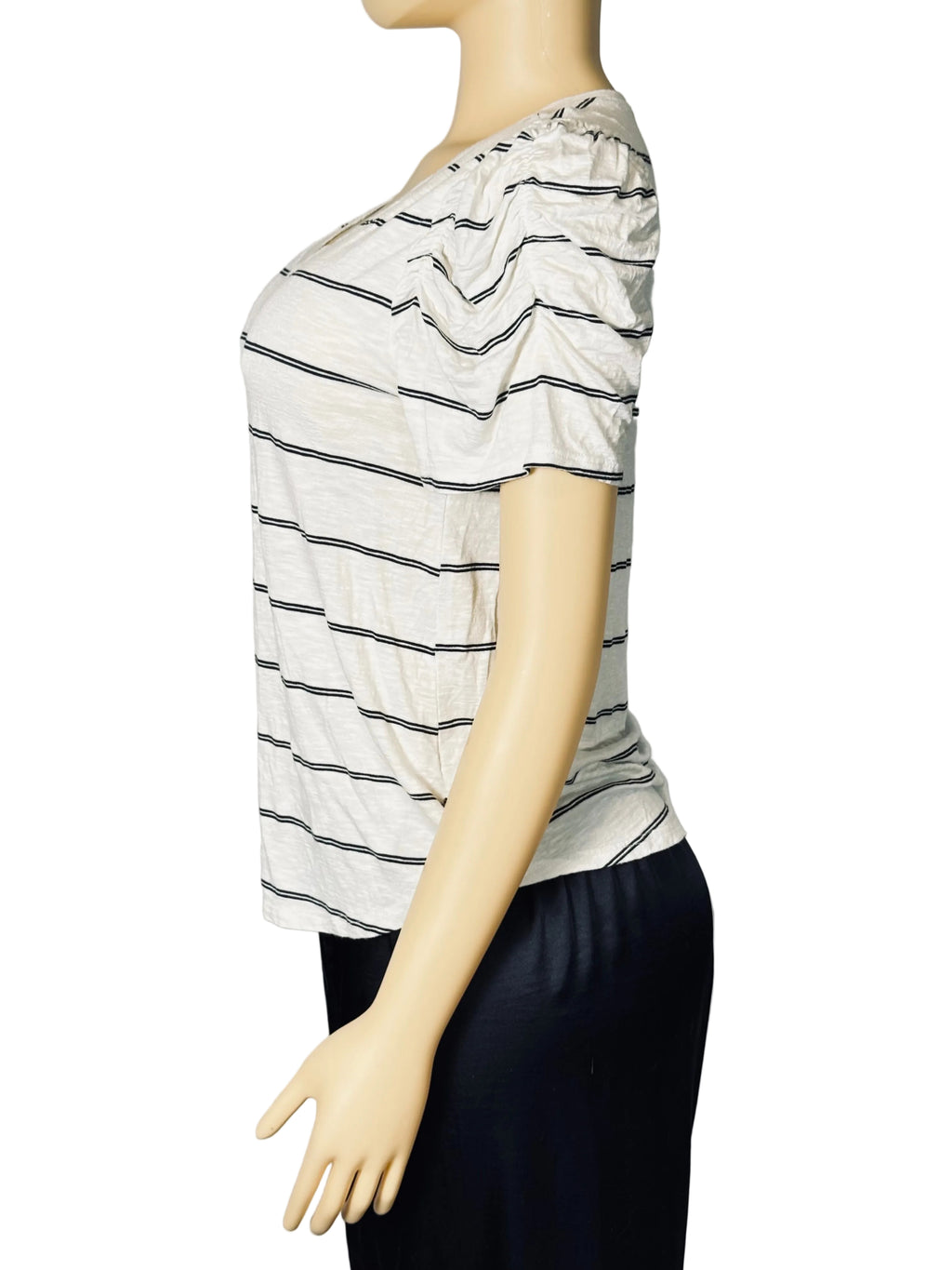 A short-sleeve striped top displayed on a mannequin torso against a light gray fabric backdrop. The top has a white base with thin black horizontal stripes and a ruffled neckline.