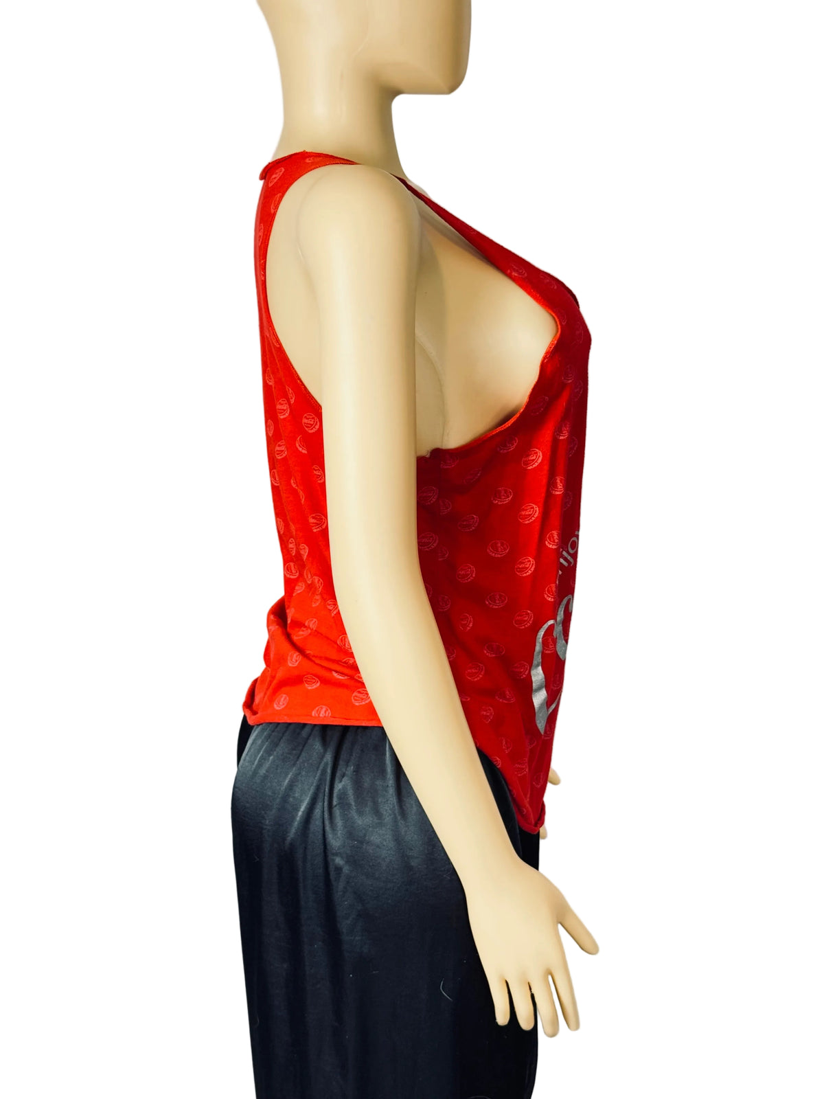 A red sleeveless scoop-neck top with a subtle tonal pattern, displayed on a beige mannequin torso alongside black pants against a white studio backdrop.