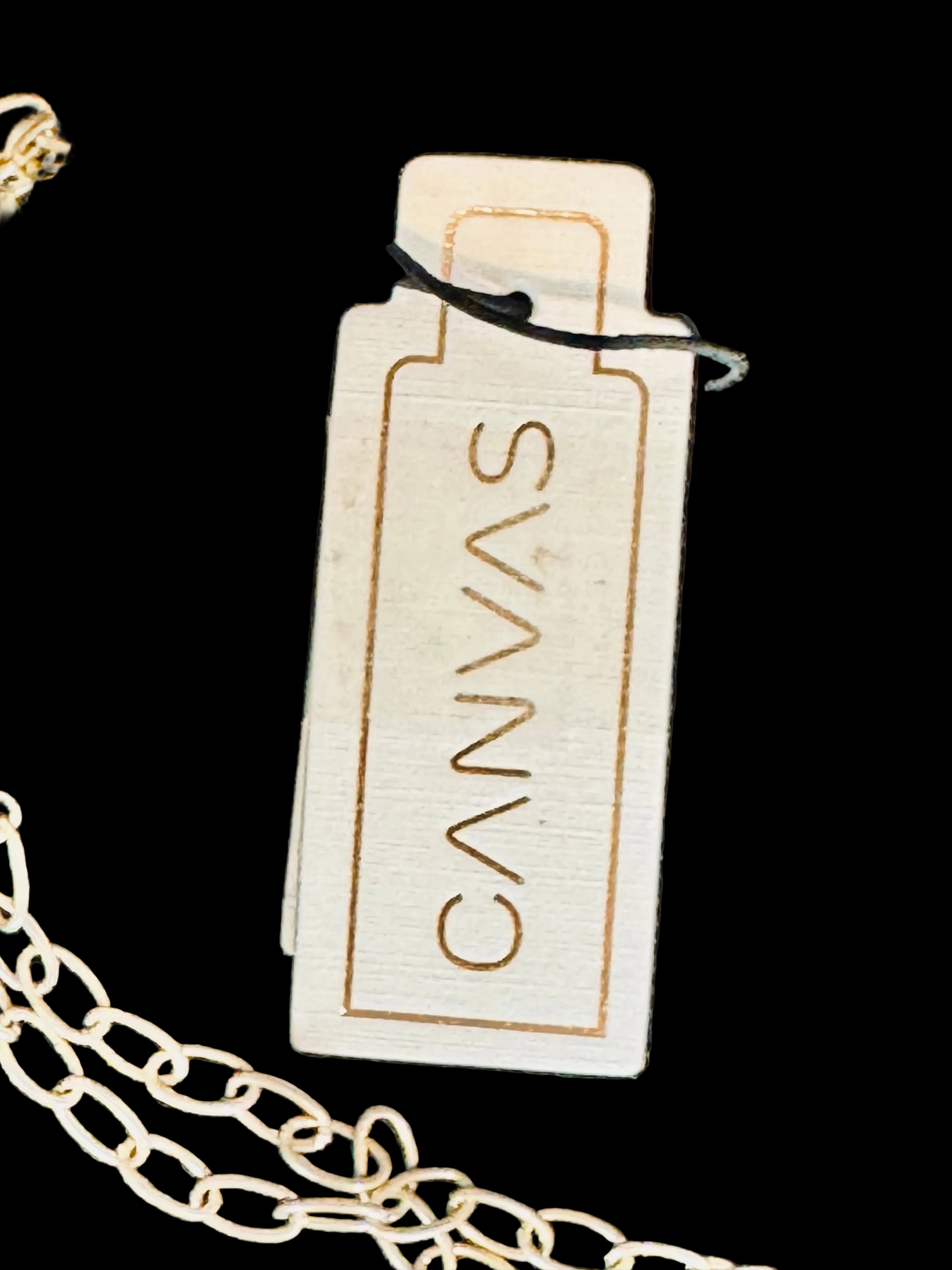 Front of Canvas Style tag from a charm necklace on a black background 