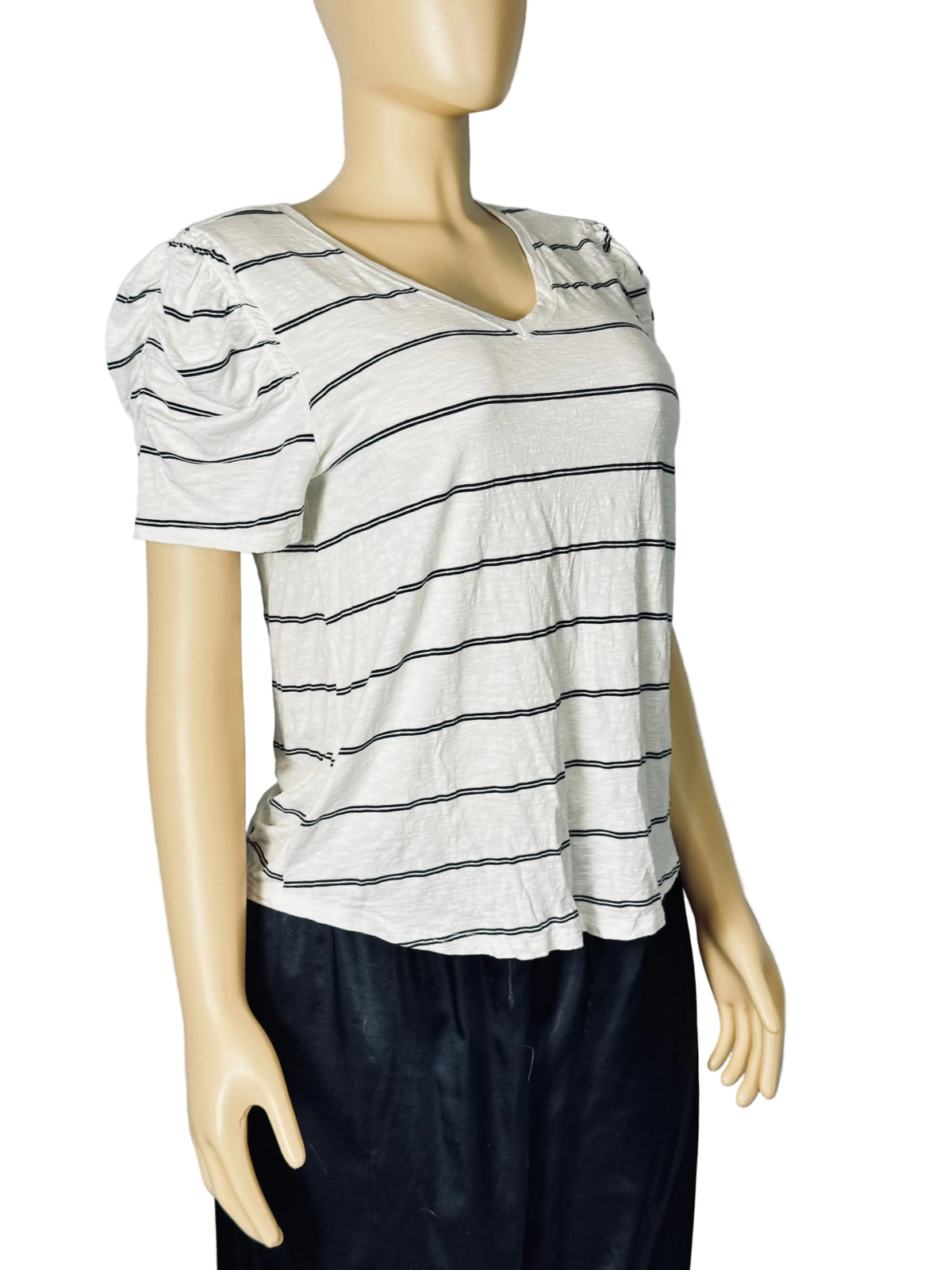 A women's short-sleeve V-neck top with thin horizontal black stripes on a light gray or off-white base, displayed on a beige mannequin torso. The top features puffed short sleeves and a relaxed fit, paired with dark pants.