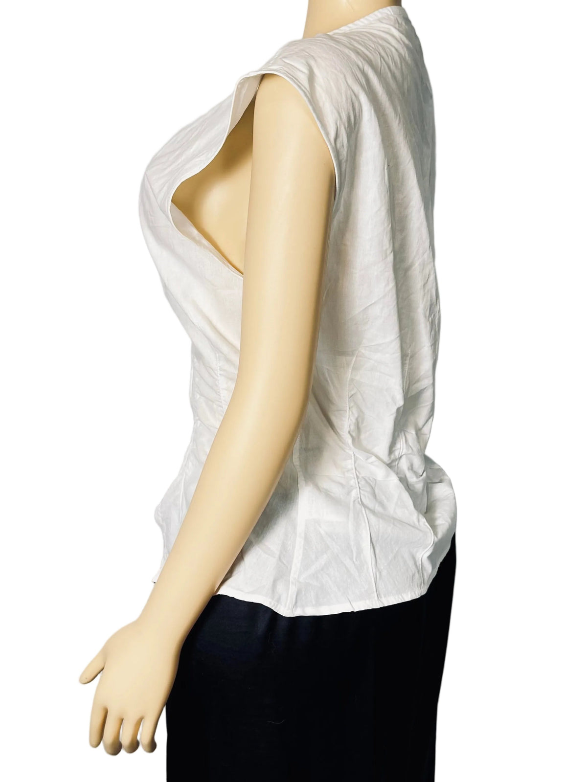 A sleeveless white top with a dramatic plunging neckline, displayed on a beige mannequin from the side against a white fabric backdrop.