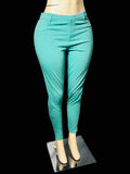 Turquoise slim-fit ankle-length pants displayed on a mannequin lower body with beige shoes, set against a white draped backdrop and gray carpet.