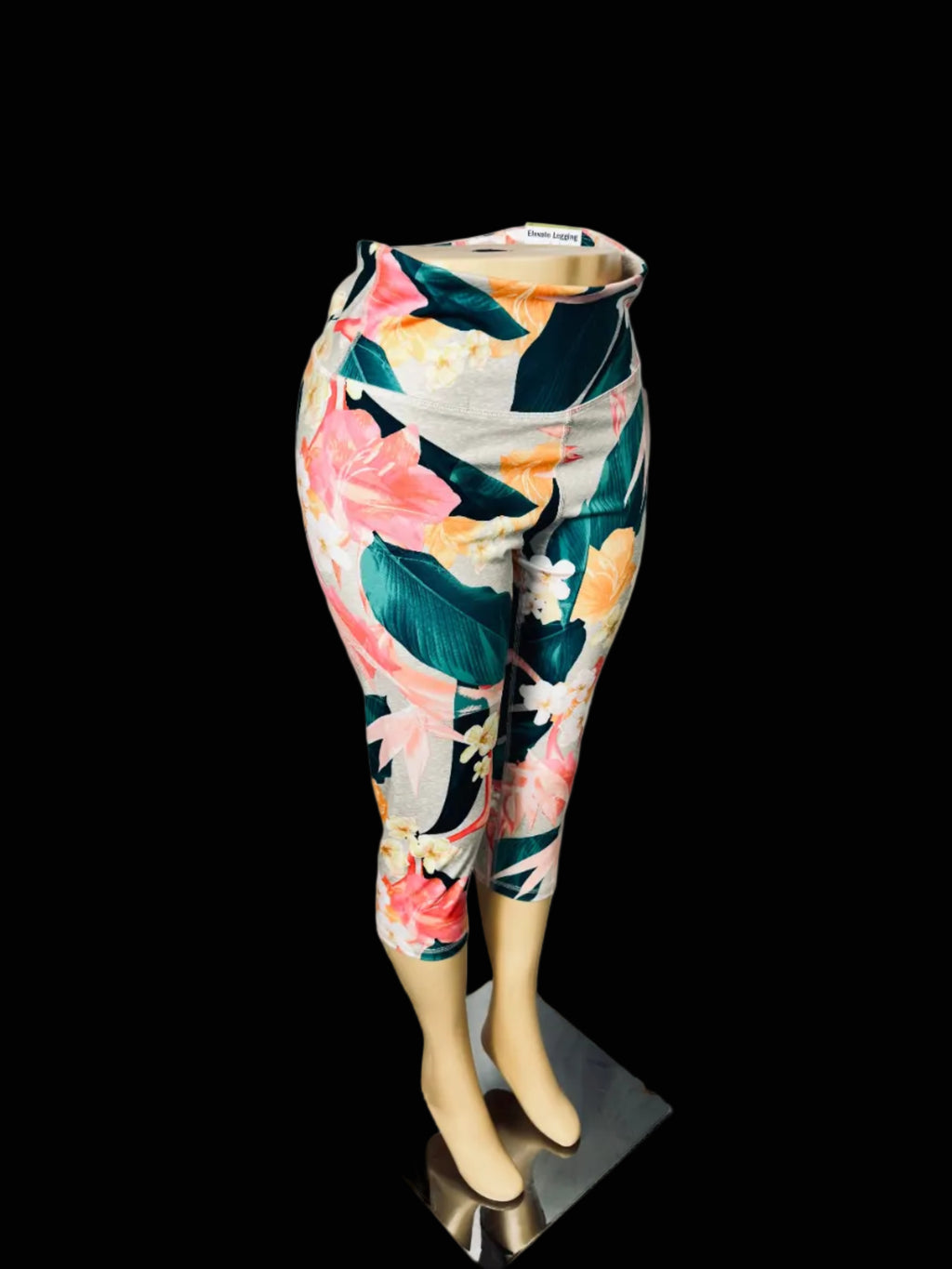 Tropical floral print 3/4 capri leggings displayed on a mannequin lower body against a white fabric backdrop.
