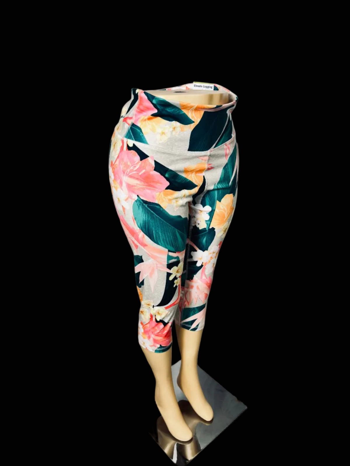 Tropical floral print 3/4 capri leggings displayed on a mannequin lower body against a white fabric backdrop.