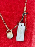 Gold necklace with a charm pendant, lobster clasp and extender chain, and new with tag on a red background