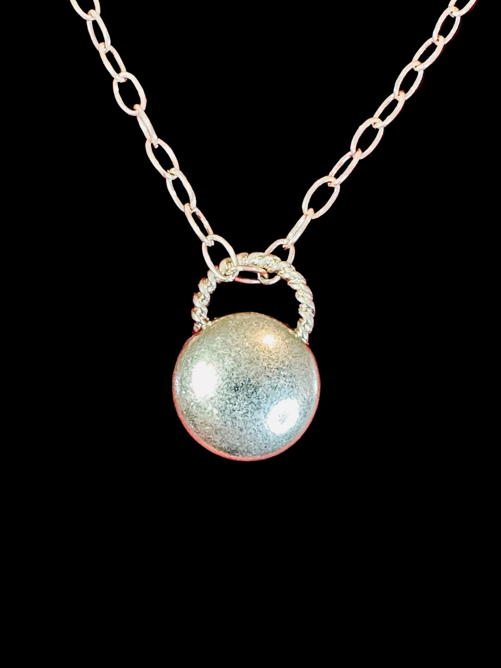 Close up image of gold toned charm holder pendant on a necklace on a red background