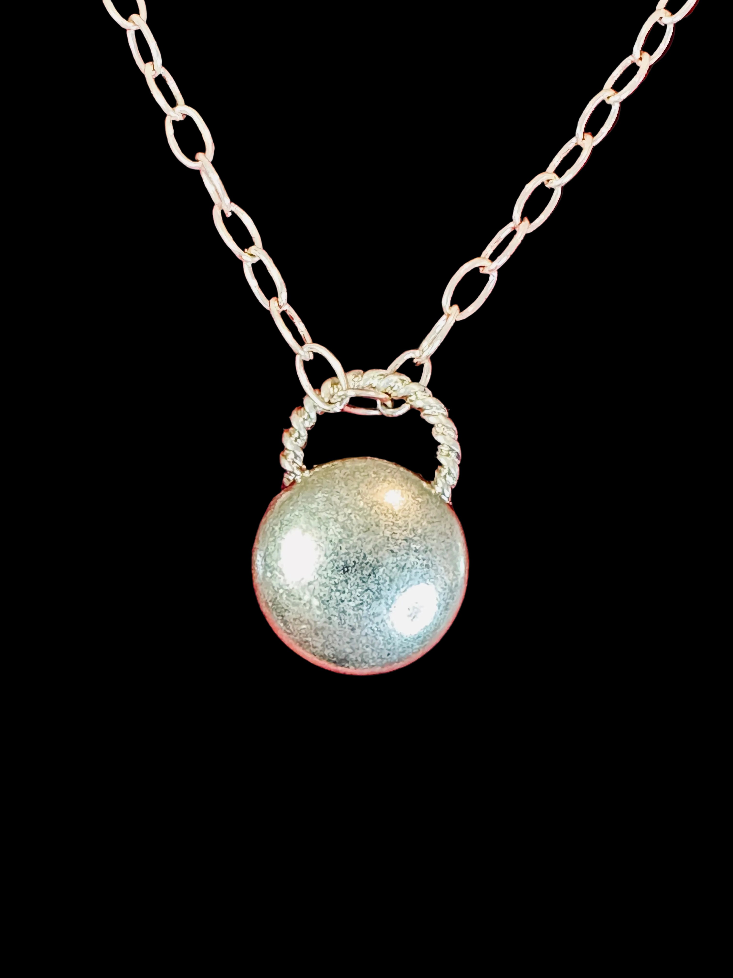 Close up image of gold toned charm holder pendant on a necklace on a red background